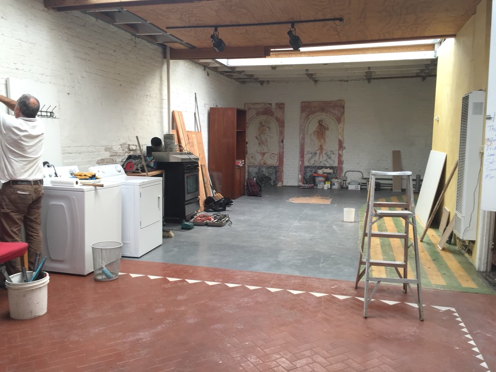 Wellness center before: from the back corner with a washer and dryer, red tile and the striped floor