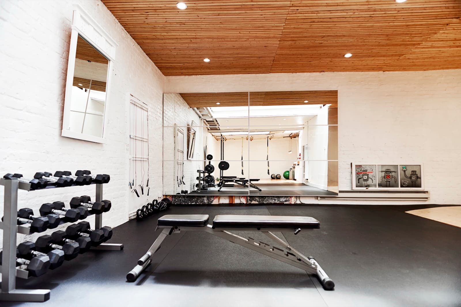 Wellness center after: dumbbell racks and benches along white brick with a mirror wall at the far end