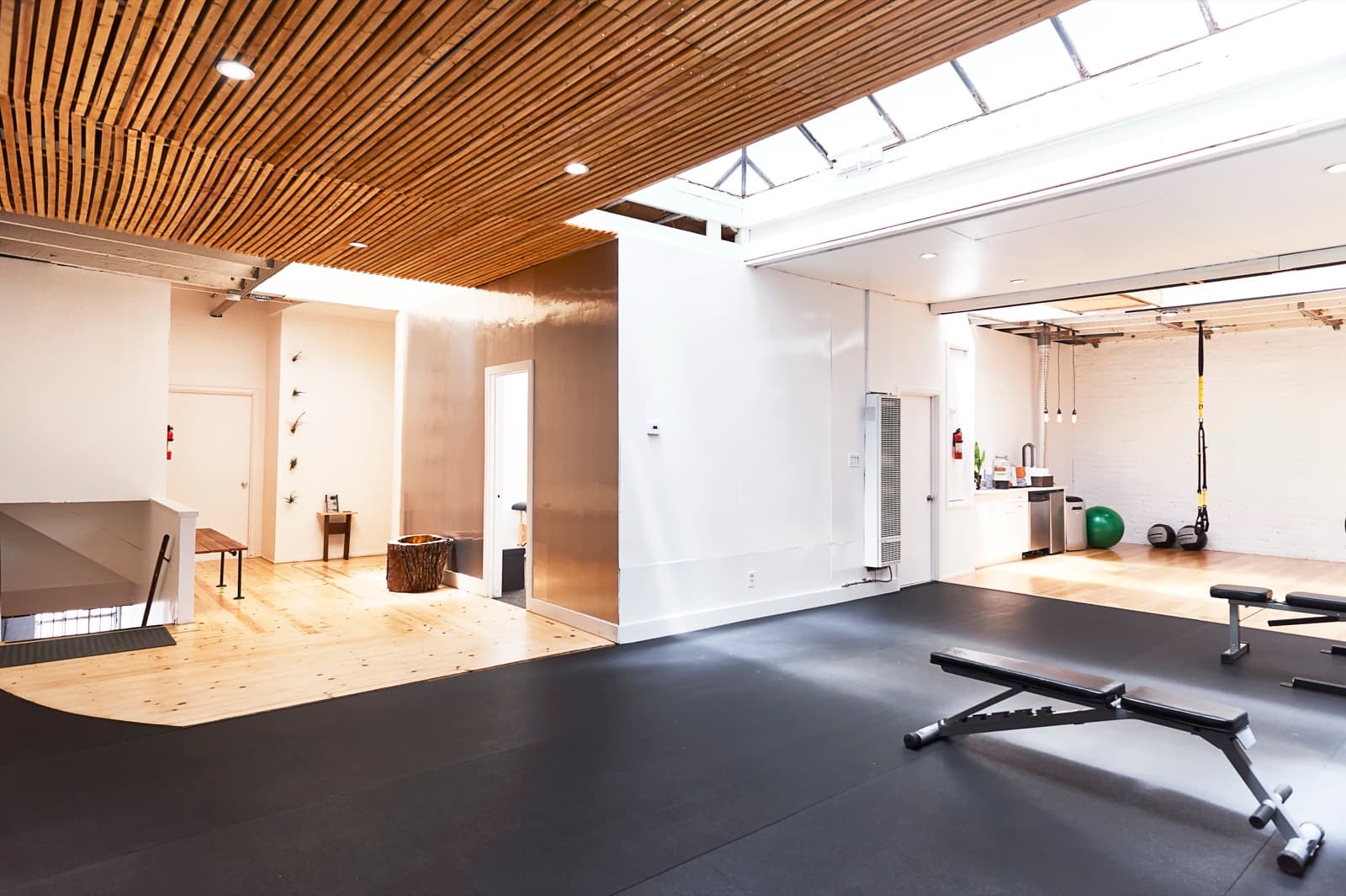Wellness center after: looking from the main room back toward the entrance, with the brushed steel partition and slat ceiling