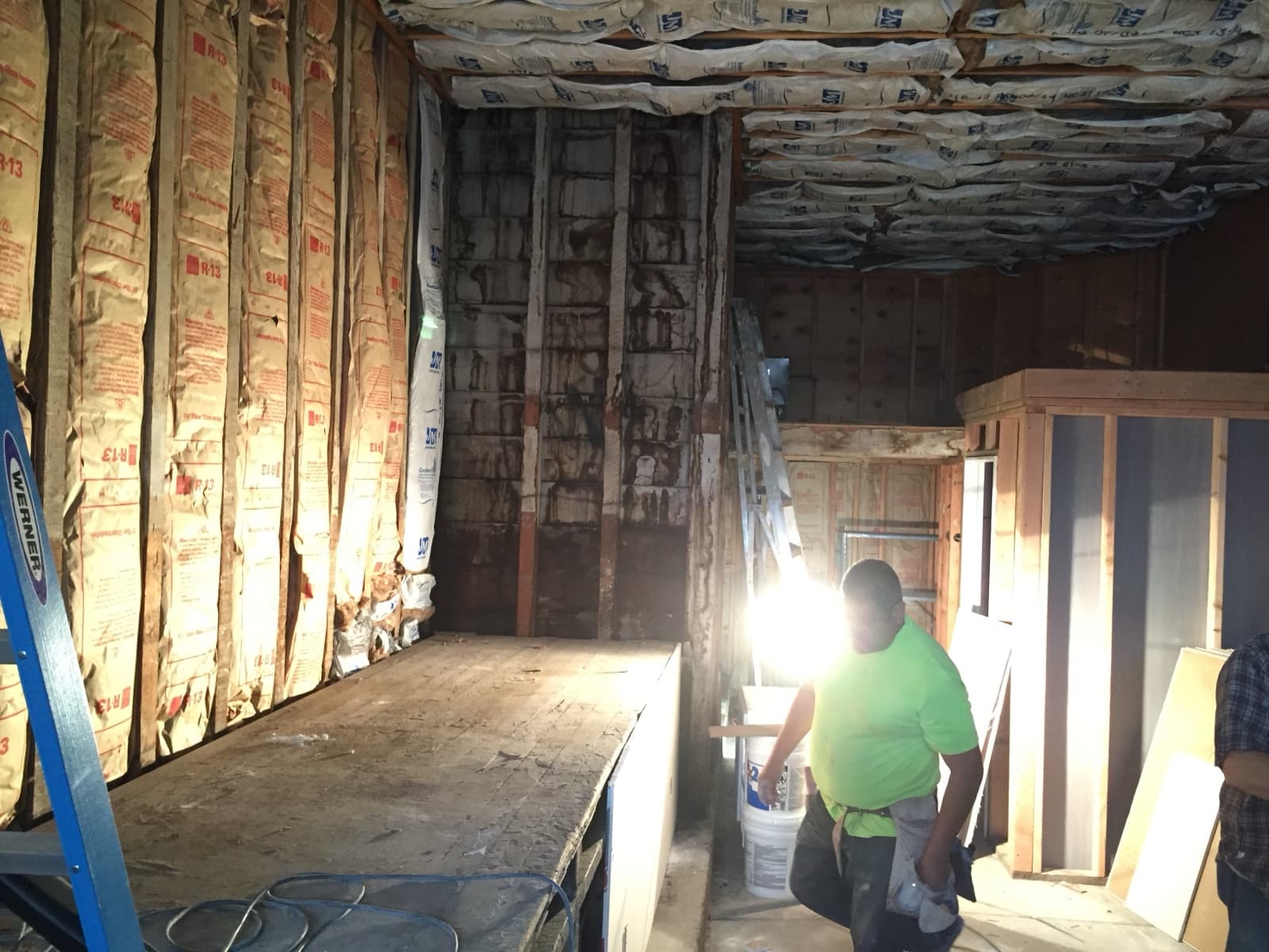 Guerrero Street garage before conversion, looking toward the back wall: bare studs with insulation, a raised plywood floor and a work light