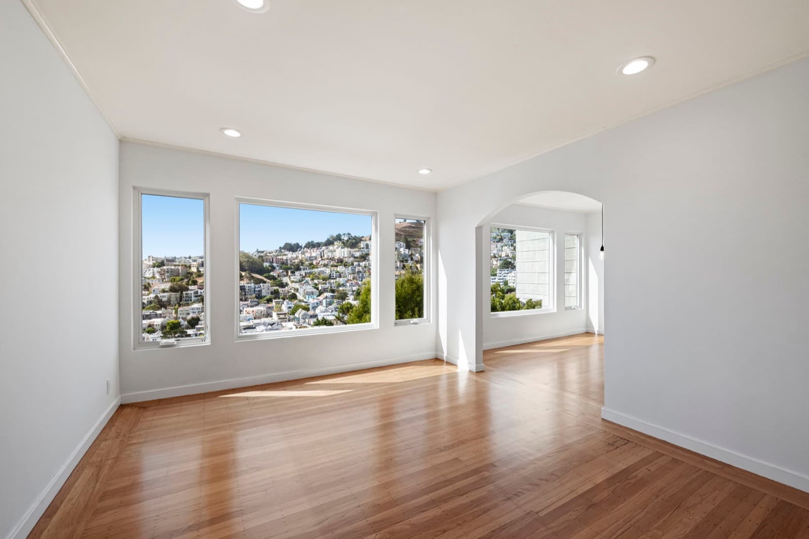Corona Heights home living room after the remodel: refinished oak floors, pale grey walls and the window wall with the city view